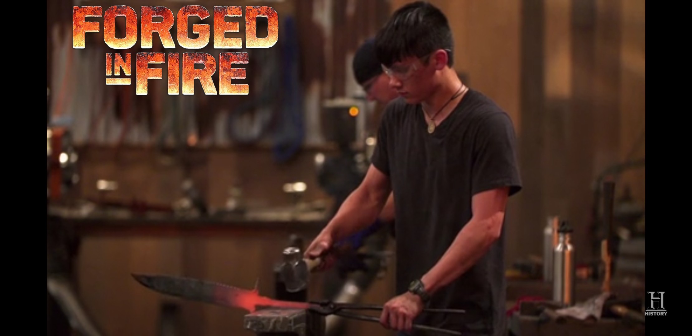 Young person working with a heated metal object in a workshop, with the text 'Forged in Fire' in the top left corner.