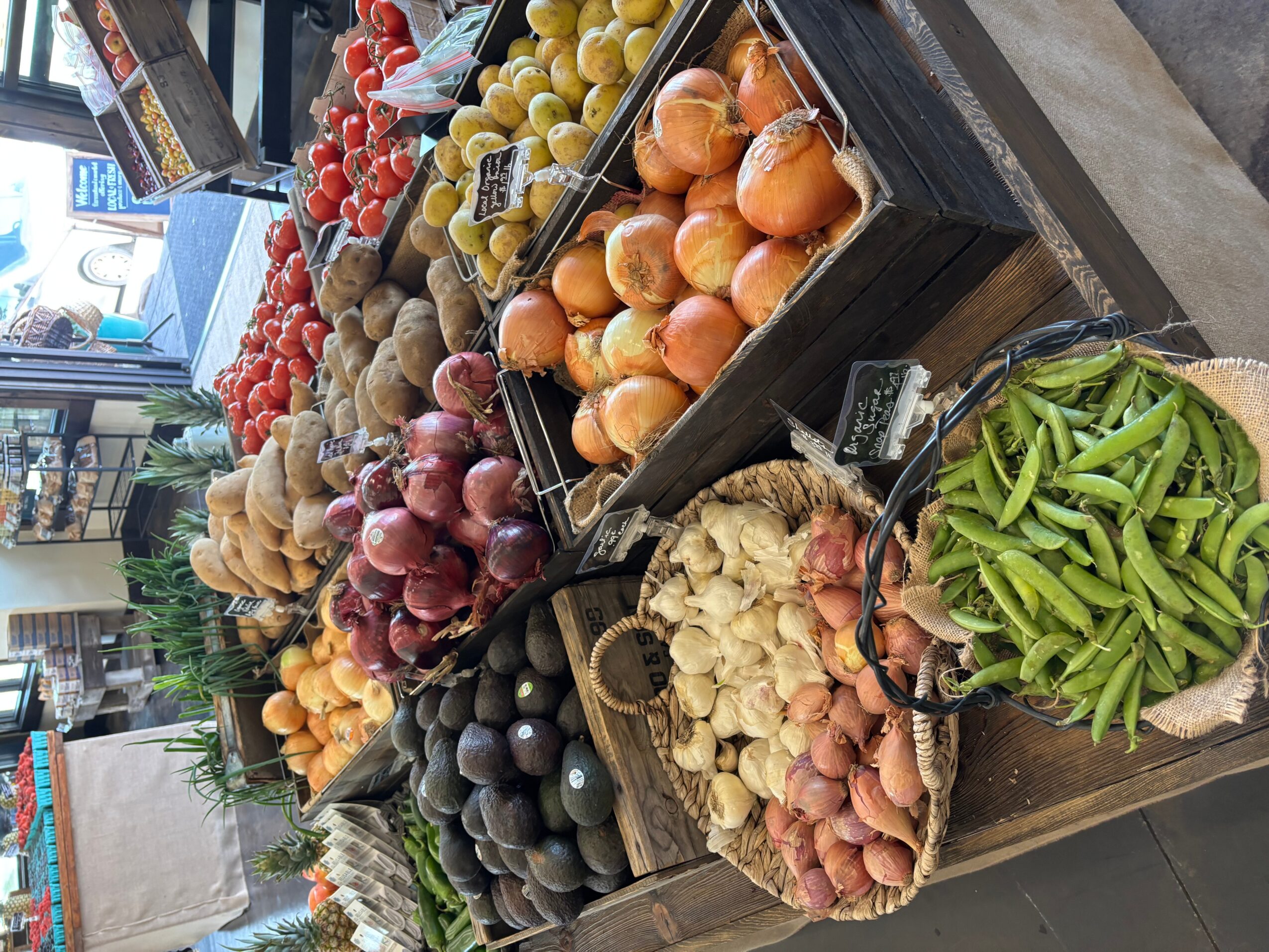 Display of various fresh fruits including apples, peaches, grapes, and green beans in baskets and containers.