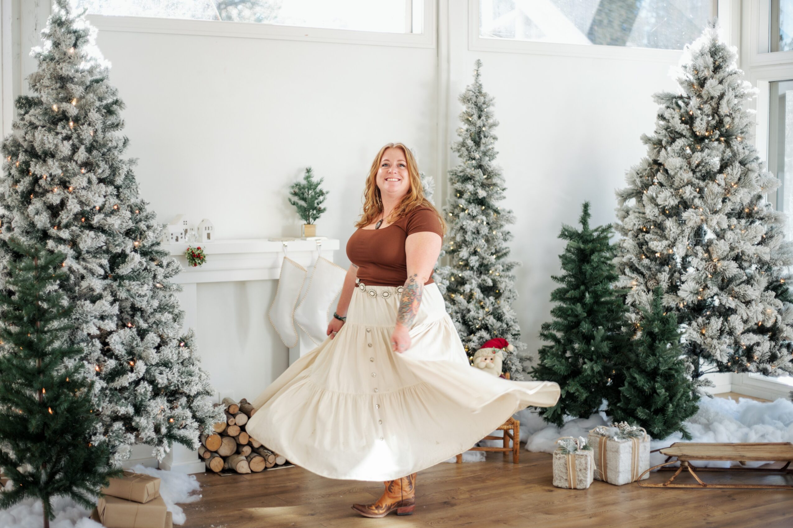 Woman in a brown top and white skirt twirling in a decorated room with Christmas trees and presents