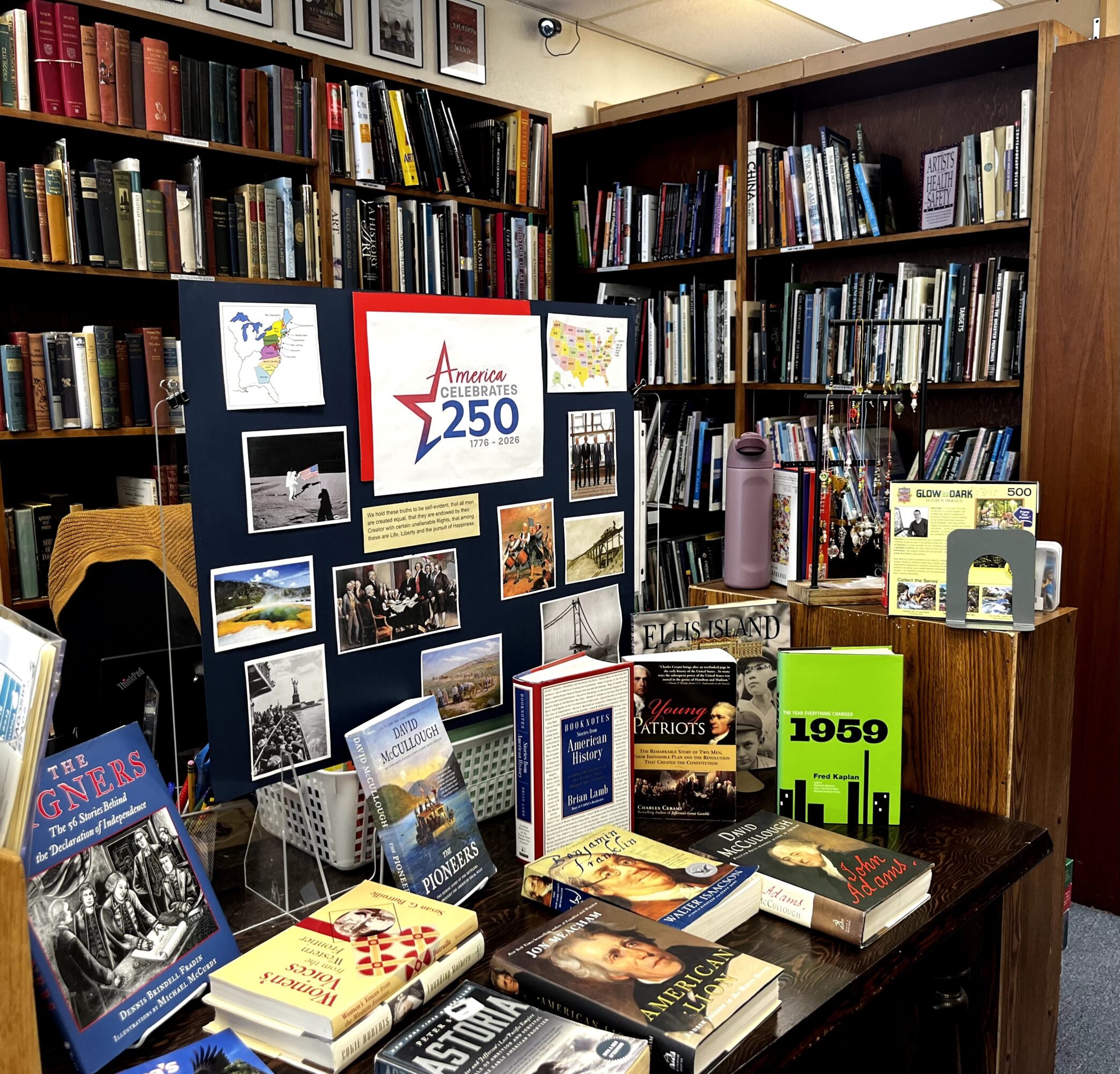 Books and display board in a library, celebrating 250th anniversary, with various books and posters on a table.