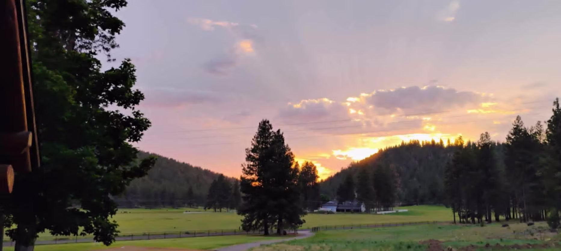 Sunset sky with clouds over a park with trees and open grassy areas.