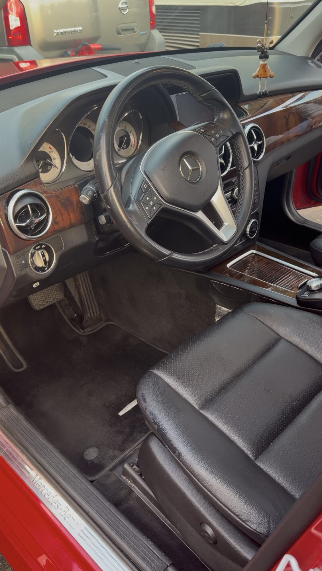 Car interior showing steering wheel, dashboard, and front seat with black leather upholstery.