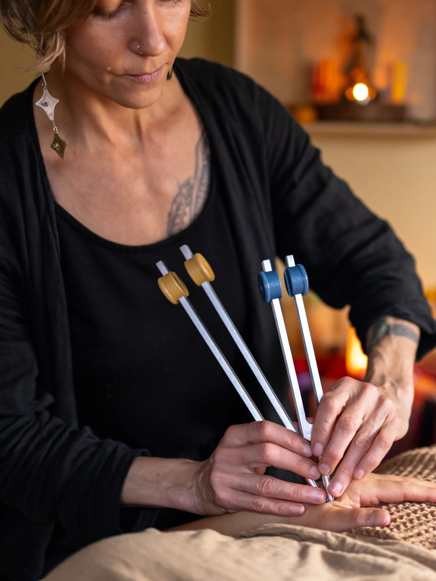 Person holding multiple knitting needles with yarn, focused on knitting, warm background, indoor setting.