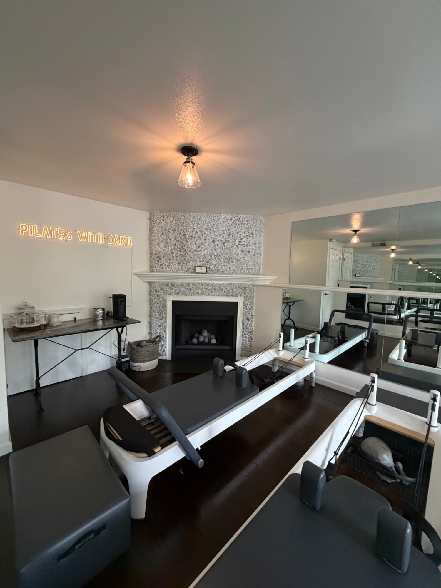 Office workspace with a desk, computer, and a vacuum cleaner, viewed from the ceiling. Bright lighting and modern decor.