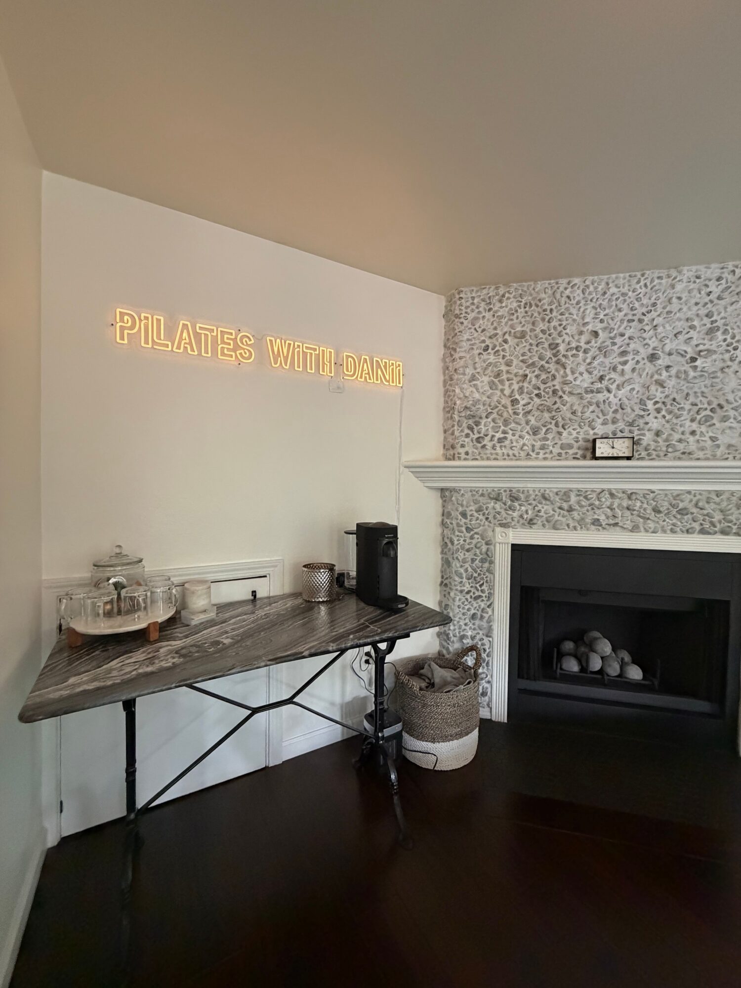 Countertop with coffee machine, grinder, and cups in a kitchen, with a sign reading 'PLEASE WASH YOUR HANDS' on the wall.