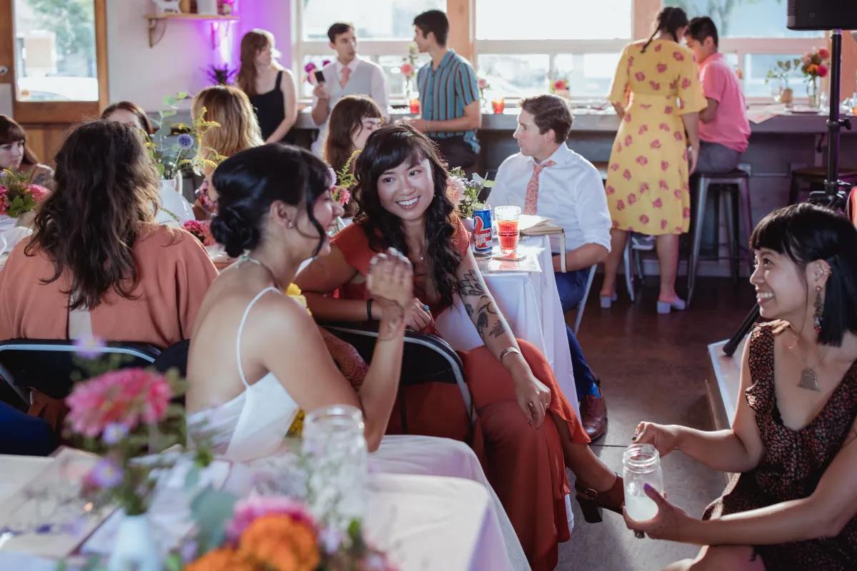 Group of women sitting at a table, smiling and talking, in a lively restaurant with other diners in the background.