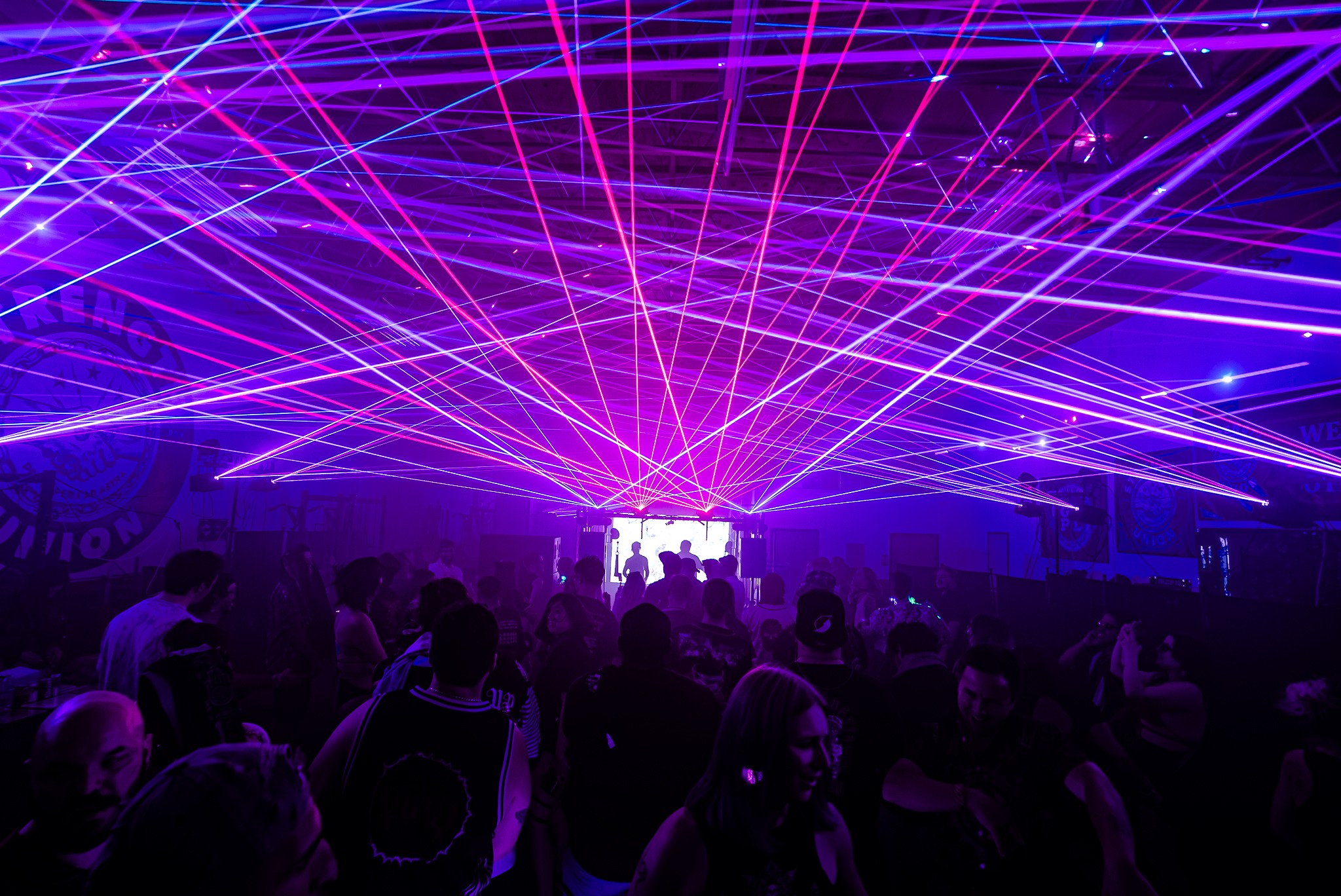 Concert scene with colorful laser lights and a crowd of people watching the stage.