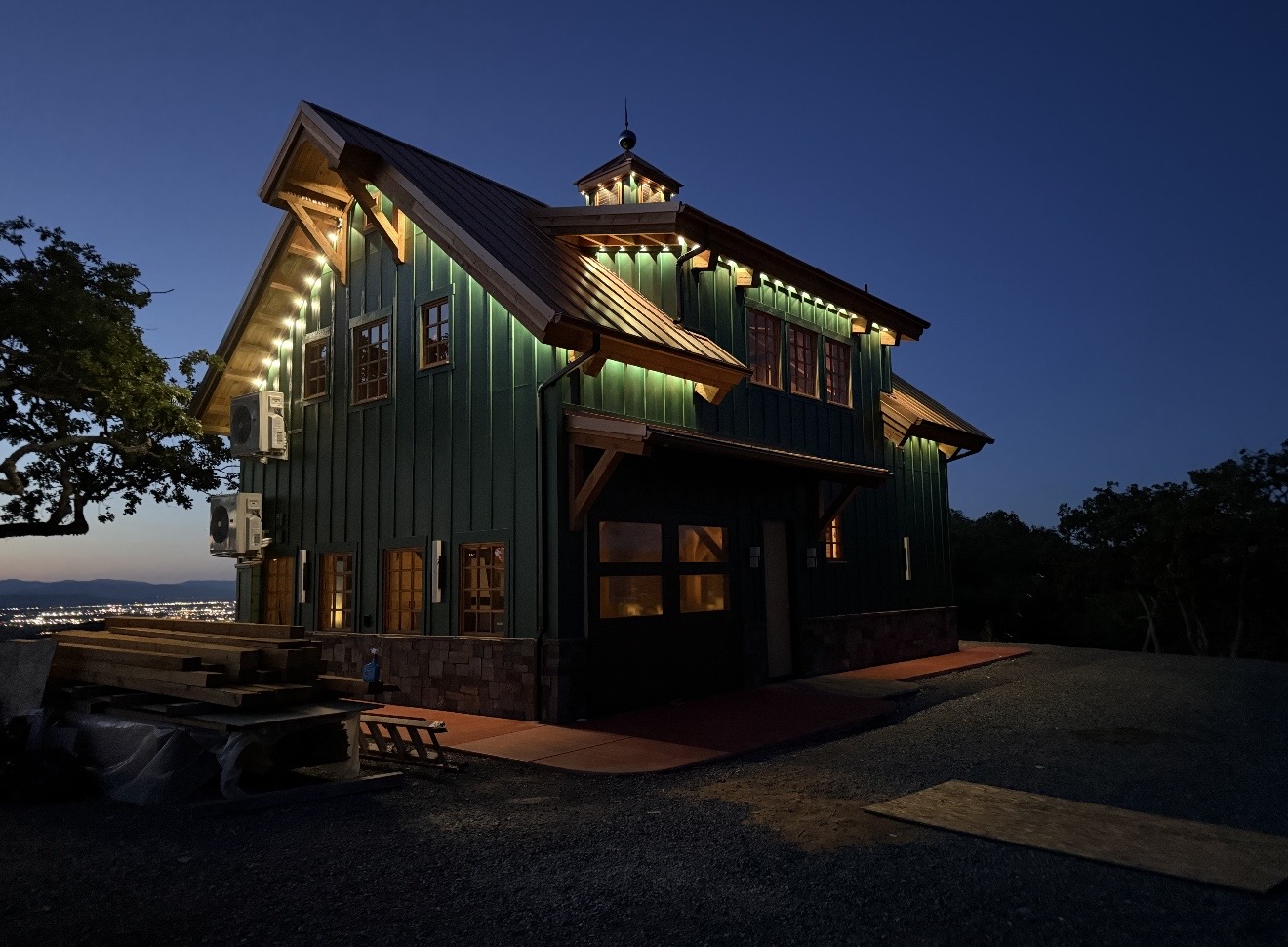 Green building with illuminated exterior lights at night, featuring a sloped roof and multiple windows.