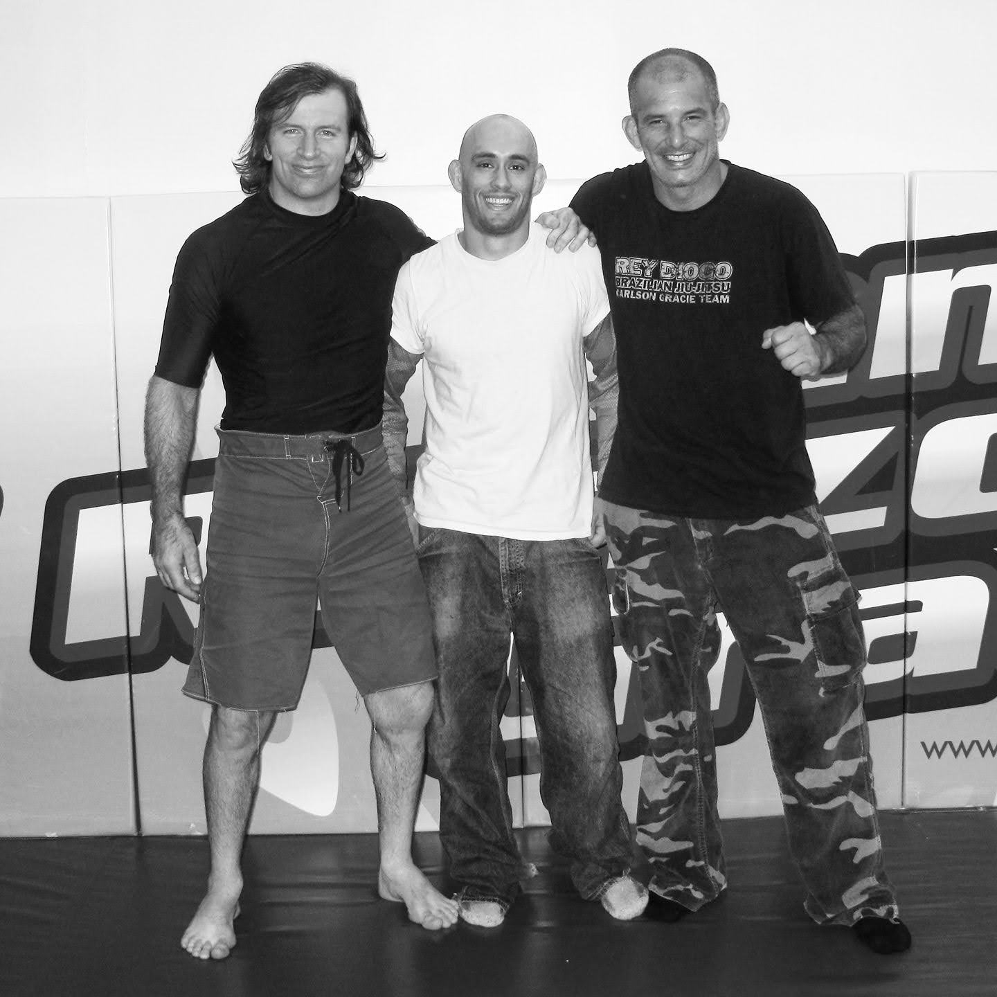 Three men stand together in front of a large printed banner.