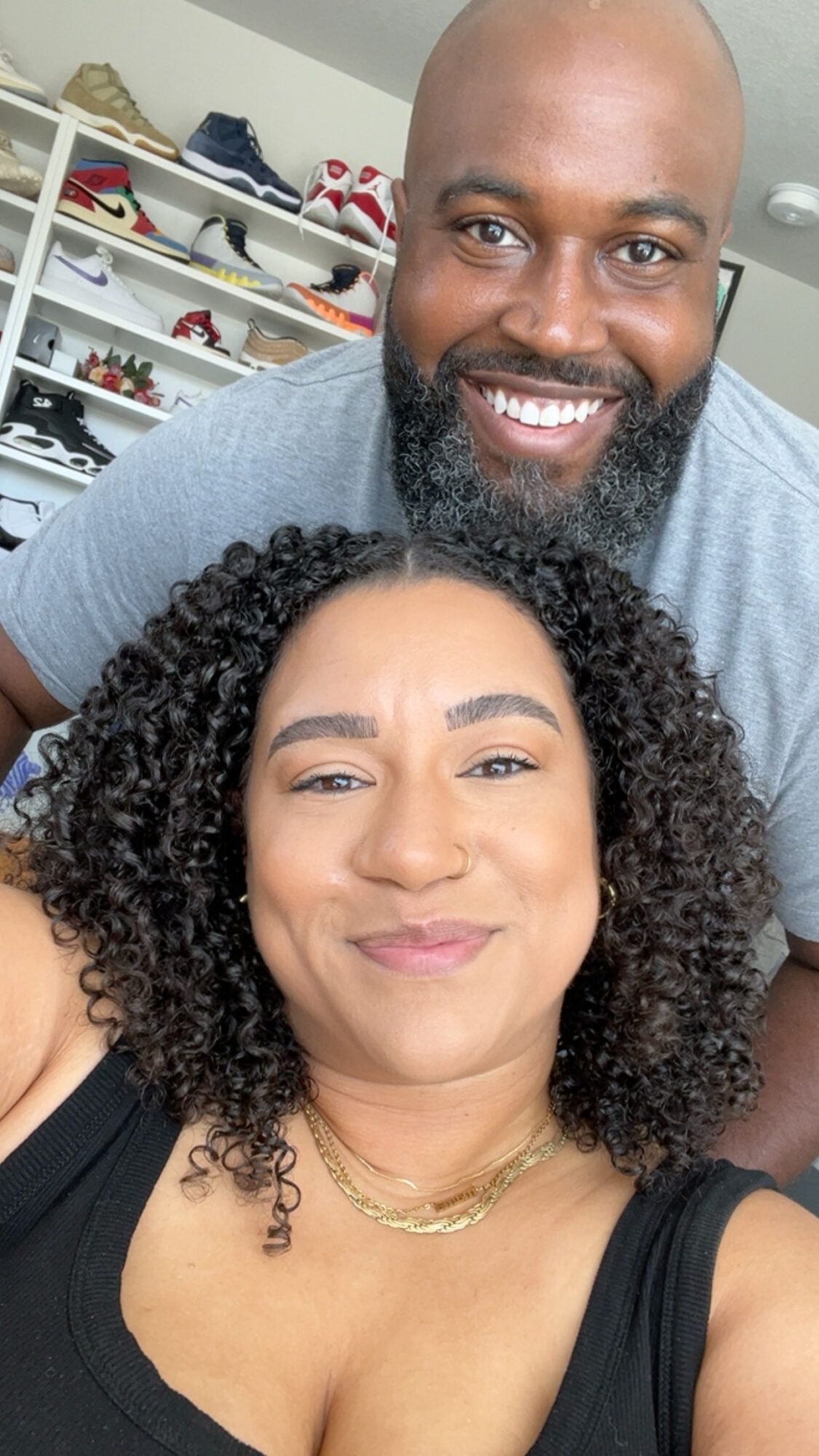 Smiling man and woman taking a selfie indoors, shelves with shoes in the background.