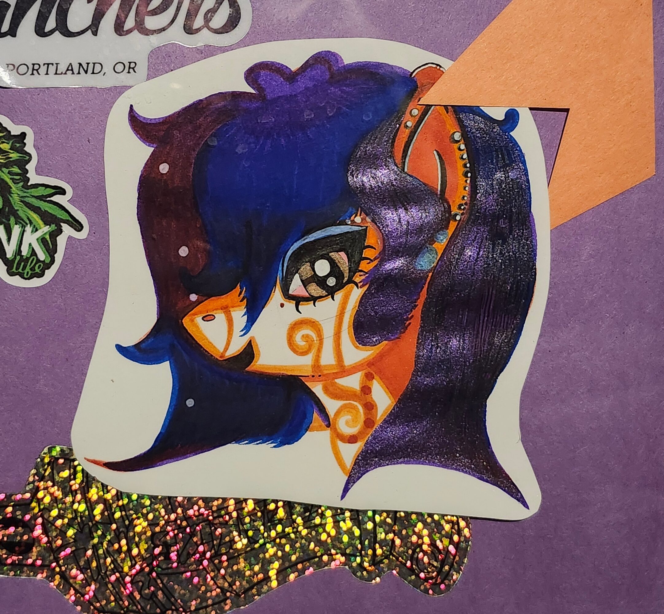 Colorful illustration of a stylized character with dark blue and purple hair, large eye, and orange decorative elements.