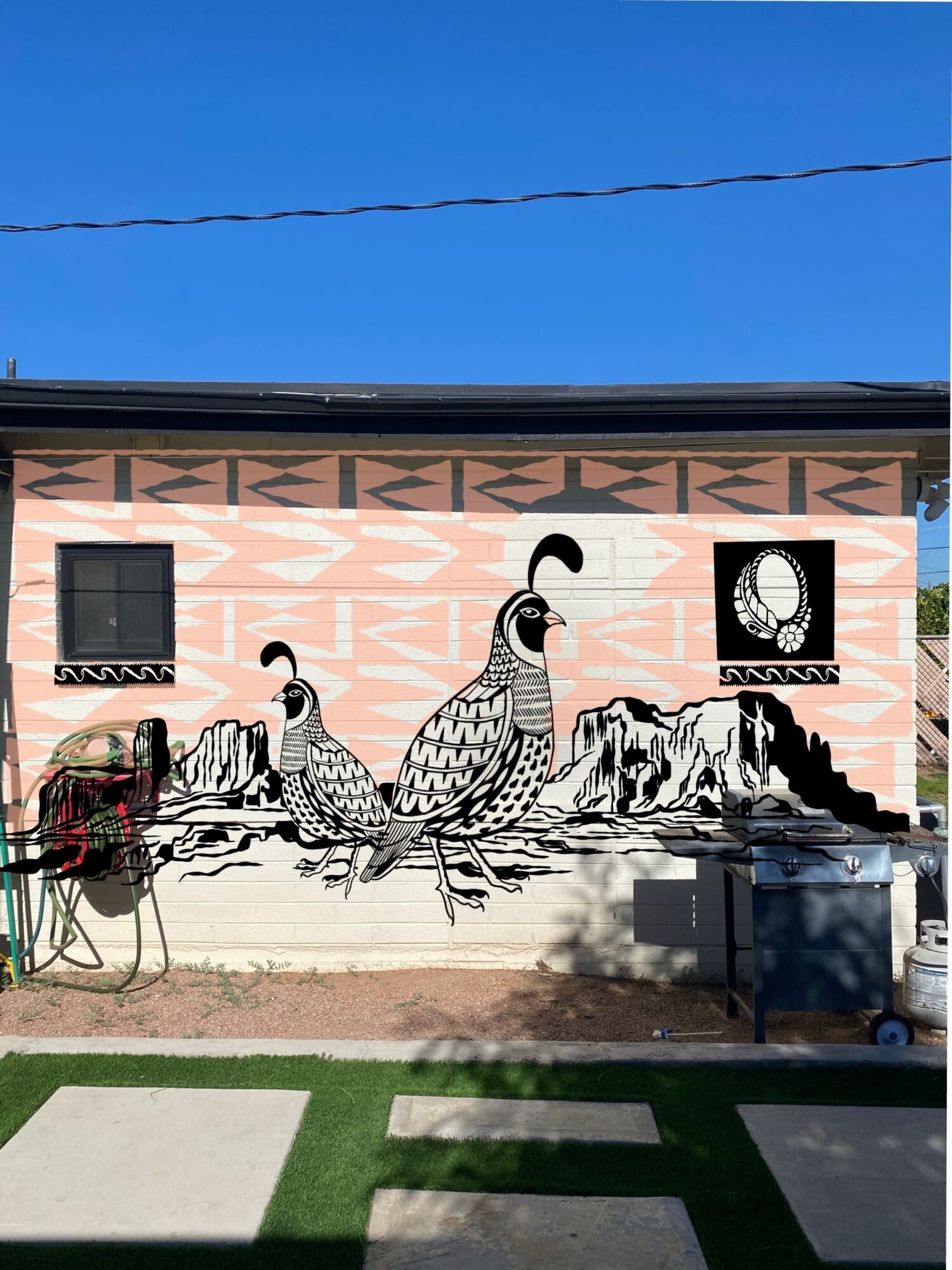Mural of three stylized birds on a pink building wall with windows and a circular design, under a clear blue sky.