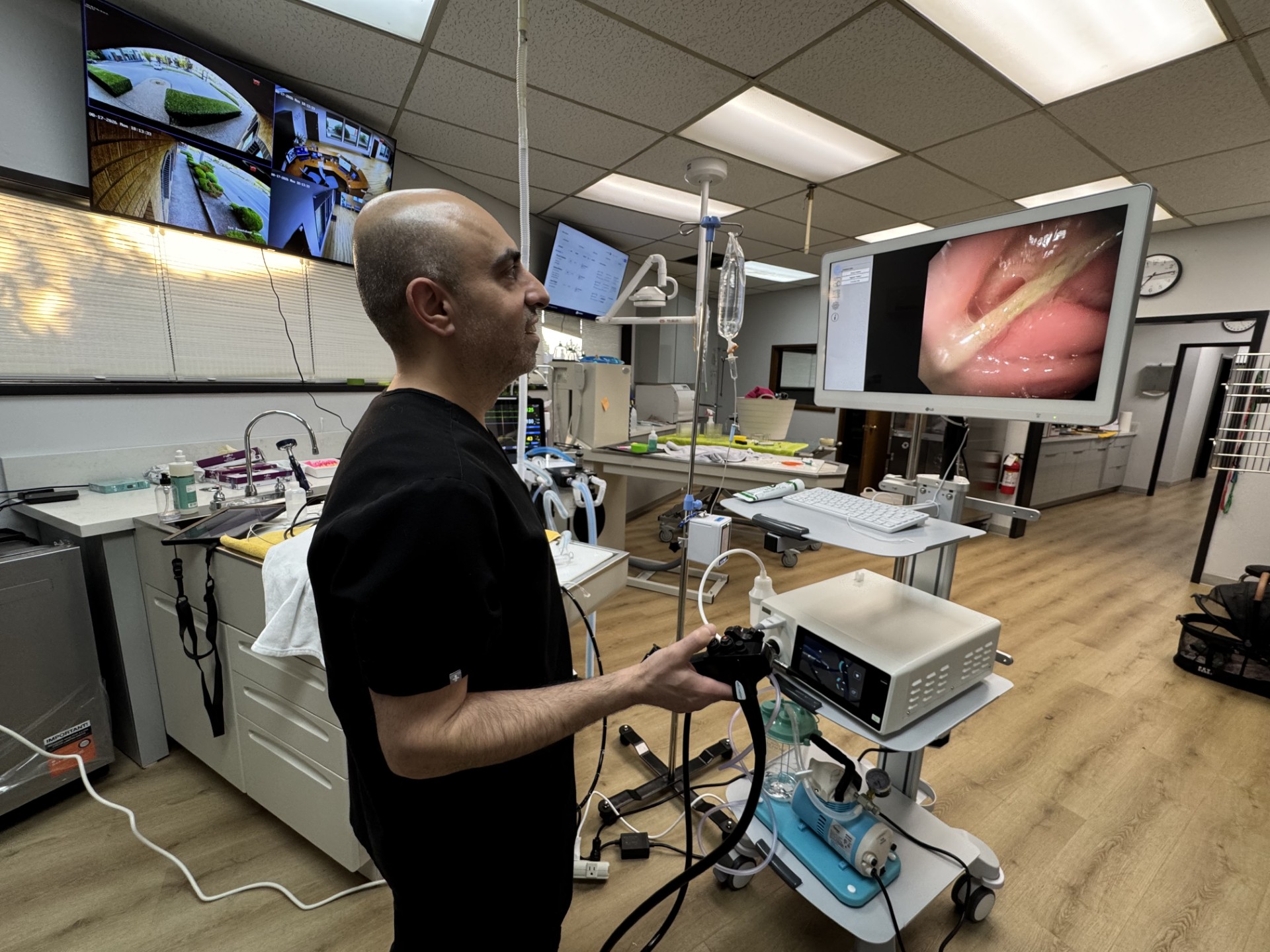 Medical professional in a clinical setting monitors a screen displaying an internal view of a body part.