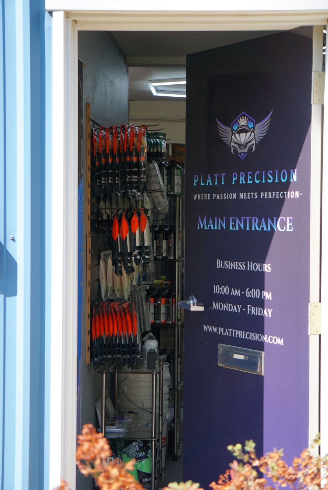 Display of paintbrushes beside a dark sign reading “Paint Precision, Maintain Excellence.”