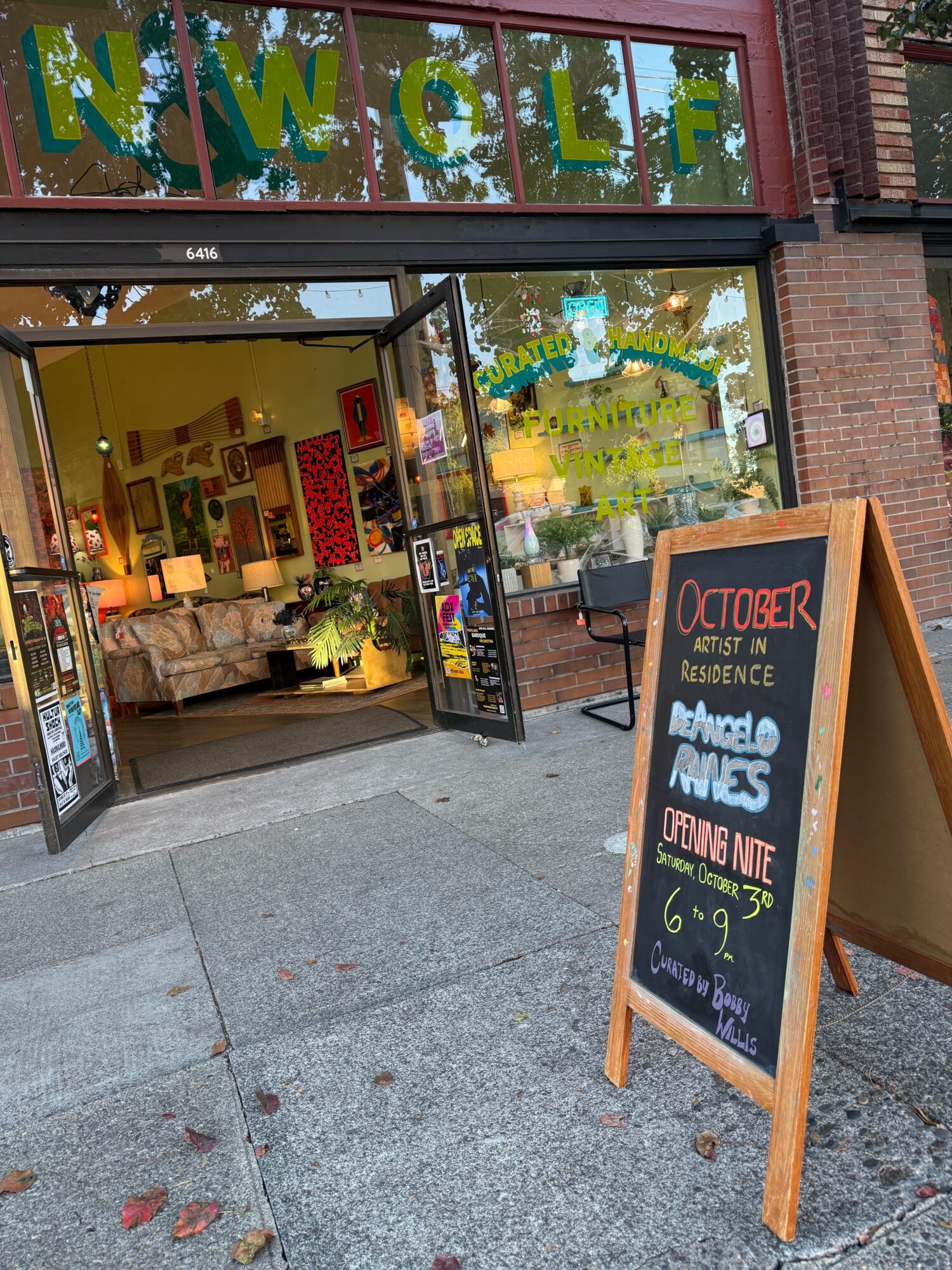 Street-facing shop with open entrance, window displays, and a sidewalk chalkboard sign.