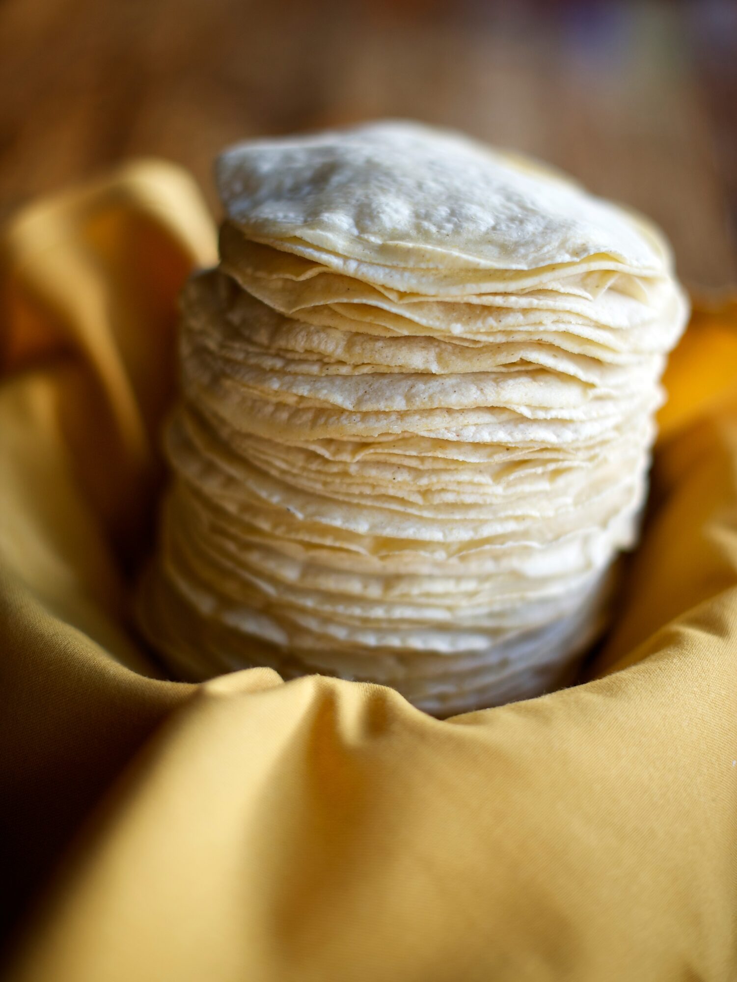 A stack of thin, round pastries rests in golden fabric.