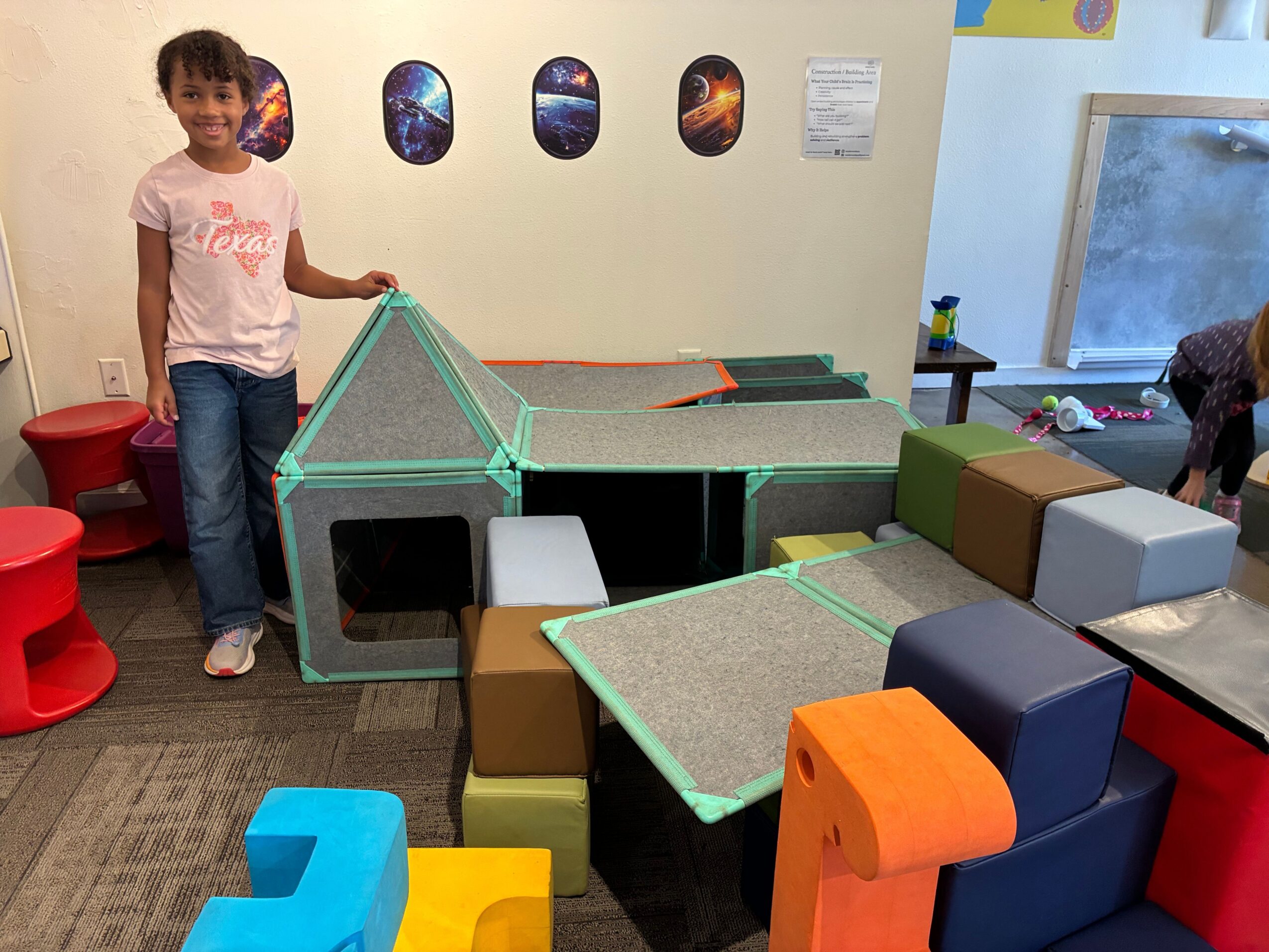 A person stands among colorful foam blocks and play equipment in an indoor room.