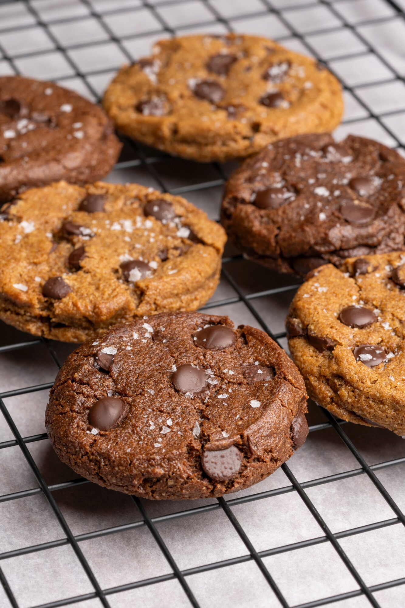 Assorted chocolate chip and chocolate cookies cooling on a wire rack.